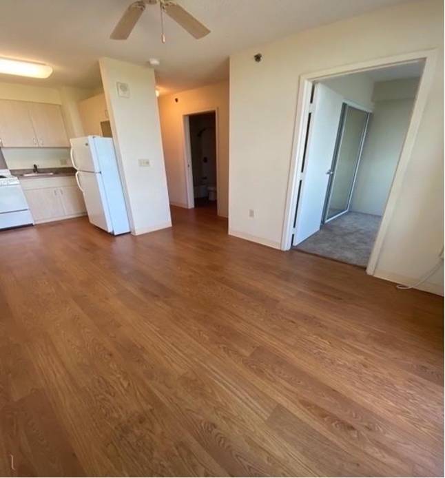 A room with wooden floors and a white refrigerator.